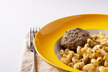 cutlet of ground beef and spinach with pasta with pesto sauce in a yellow plate