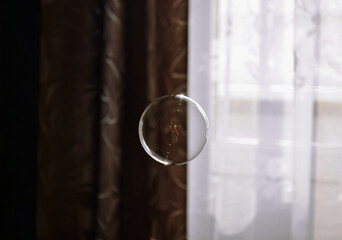 Perfectly round transparent soap bubble on a brown and white background