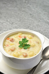 Bowl of potato soup with vegetables and pieces of meat on marble gray background Vertical shot from a high angle and copy space.