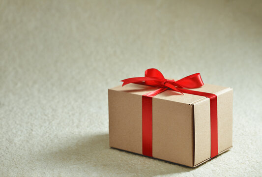 Gift Box Tied With A Red Ribbon With A Bow On Yellow Marble Background Studio Shot From A High Angle. With Copy Space.