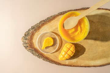 A yellow smudge of a mango body scrub and a natural mango soap lying on a wooden tray