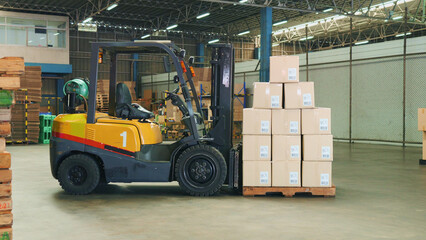 Side view of a forklift with stacked cargo cardboard boxes on wooden pallet in a large warehouse...