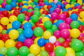 Many colour plastic balls from children's small town. Background texture of multi-colored plastic balls. Colorful plastic gum balls in kid playroom or playground for children's holiday party concept