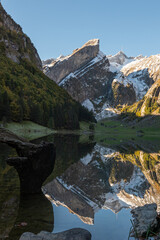 Seealpsee, Alpstein Region, Appenzell, Innerrhoden, Switzerland: The famous Säntis covered in snow with a perfect reflection on a sunny day in autumn. 
