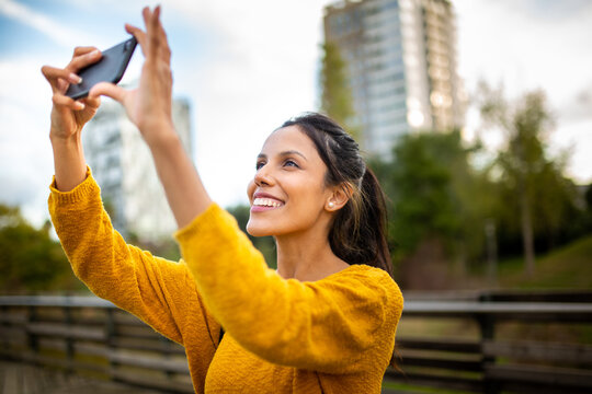 smiling young woman taking photo with mobile phone