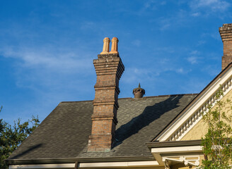 Shingled Roof of Historic Home with Vintage Brick Chimney, Antique Clay Chimney Pots and Antique...