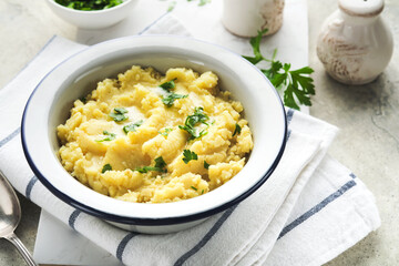 Mashed potatoes. Hot mashed potatoes with butter, fresh parsley herbs and pepper in bowl on slate, stone or concrete backgrounds. Delicious creamy mashed potatoes. Top view.