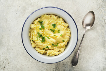 Mashed potatoes. Hot mashed potatoes with butter, fresh parsley herbs and pepper in bowl on slate, stone or concrete backgrounds. Delicious creamy mashed potatoes. Top view.