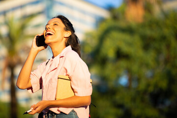 Side of happy young woman talking and laughing with cellphone