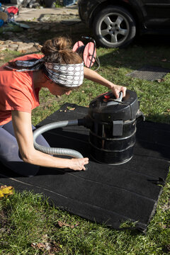 Woman Cleaning Carpet from Her Car with a Vacuum Cleaner  in the Home front yard