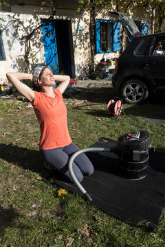 Smiling Mid Adult Woman Relaxing and Stretching While taking a break from  Cleaning Carpet from Her Car with a Vacuum Cleaner  in the Home front yard