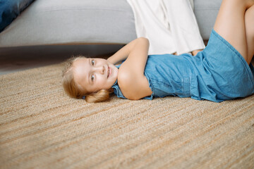 little girl is playing lying on the floor in the living room . - Powered by Adobe