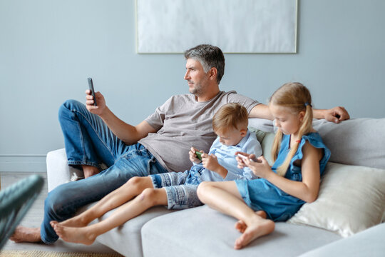 father and two children using their smartphones in their free time.