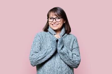 Portrait of smiling middle aged female looking at camera on pink background