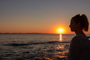 Silhouette of tourist woman holding the sun with panoramic view of sunset over Aegean Mediterranean Sea on Karydi beach, peninsula Sithonia, Chalkidiki (Halkidiki), Greece, Europe. Romantic atmosphere