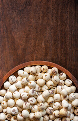 Dried lotus seeds in a wooden tray on a rustic wooden floor with copy space, close up, flat lay.