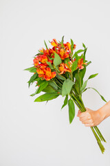 Women's hand hold orange flowers bouquet on white background. Spring floral concept.
