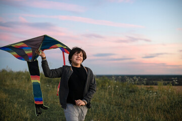 A teenager launches a kite at sunset in the summer in a field. The concept of hobbies, recreation and entertainment.	
