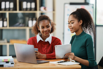 Focused young african american businesswoman or student looking at laptop holding book learning, serious black woman working or studying with computer doing research or preparing for exam online