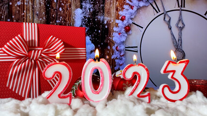 Happy New Year 2023 made by candles on a festive Christmas background with Clock Dial. Five minutes...