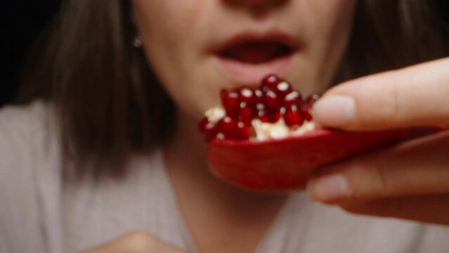 Extreme close-up of a girl eating a slice of pomegranate.