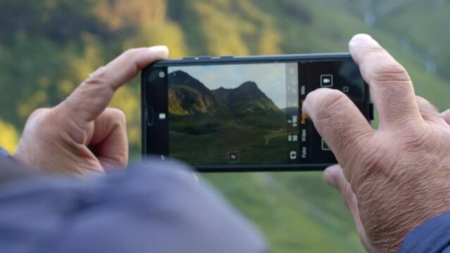 Man taking a landscape photograph with his mobile phone from a foreshortened position