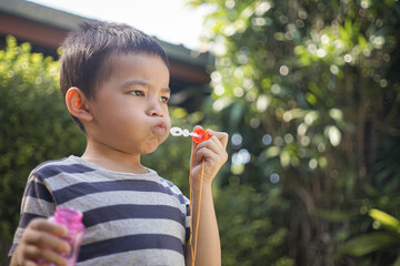 Little boy with soap bubbles in summer park.
