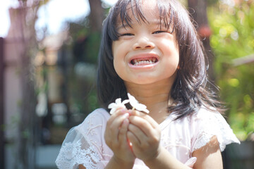 cute little asian girl holding a white bouquet. Child planting spring flowers. 