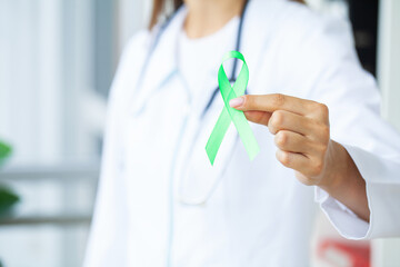 Young woman holding awareness green ribbon as a symbol to awareness Lymphoma cancer