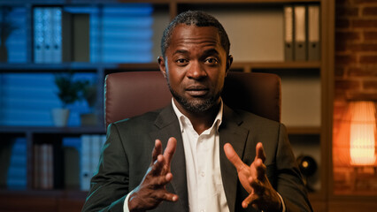 Serious professional businessman looking at camera negotiating on video call smart adult male...