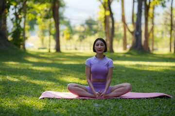 Yoga in the park. Young Asian woman practicing yoga pose at the park.