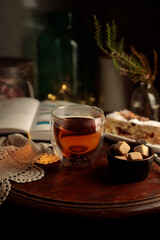 Hugge evening with a cup of tea, a book and dessert. A hot drink on a round wooden table, a book and a piece of homemade cake