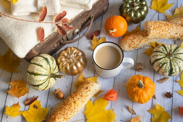 Mug of hot coffee, colorful pumpkins and autumn leaves on a wooden background. Autumn still life.