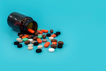 Multicolored medical pills and capsules with a bottle on a blue background. Medical drugs with free space for an inscription. Health