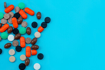 Multicolored medical pills and capsules with a bottle on a blue background. Medical drugs with free space for an inscription. Health