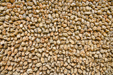 Unusual background of small pointed natural stones attached to a concrete wall