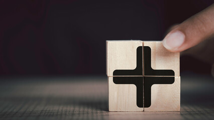 Plus sign in wooden cube block stack. added value, benefits, additional, personal development,...