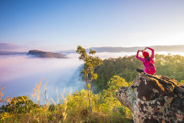 Young woman in red jacket hiking on Pha Muak mountain, border of Thailand and Laos, Loei province, Thailand.