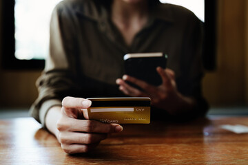 Portrait of young Asian woman using credit card and phone for online shopping