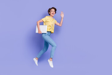 Fototapeta na wymiar Full length portrait of crazy amazed person jump rush hold netbook arm waving hi isolated on purple color background