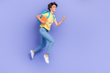 Fototapeta na wymiar Full length portrait of carefree active person carry bag hold book jump rush isolated on purple color background