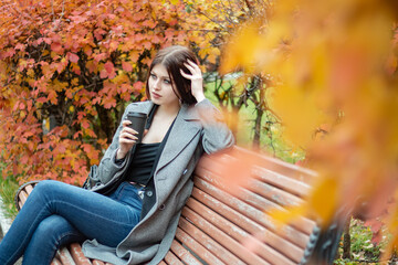 Girl with a cup of coffee in the autumn park.