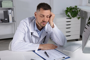 Naklejka premium Exhausted doctor sleeping at workplace in hospital
