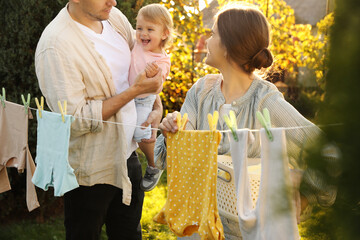 Happy family near washing line with drying clothes in backyard