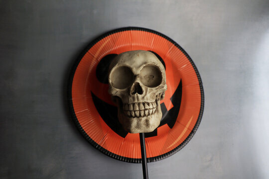 human skull on halloween decorated plate with pumpkin