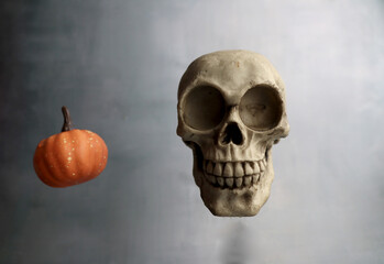 floating human skull and pumpkin isolated on grey background