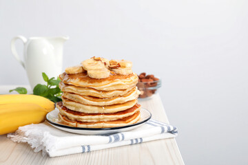 Tasty pancakes with sliced banana served on white wooden table. Space for text