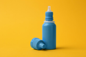 Bottle of medical drops on yellow background