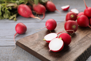 Fresh ripe radishes on grey wooden table, closeup. Space for text