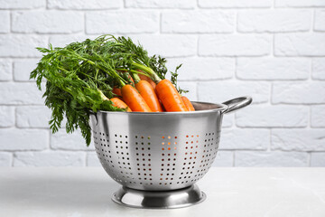 Colander with fresh ripe carrots on marble table - obrazy, fototapety, plakaty